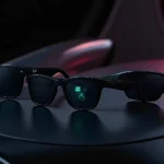 Trois modèles de lunettes connectées Meta 2025 posées sur une surface sombre : Ray-Ban Meta Gen 2 au style Wayfarer, Meta Ray-Ban Display avec affichage holographique vert dans le verre droit, et Oakley Meta Vanguard au design sportif noir.